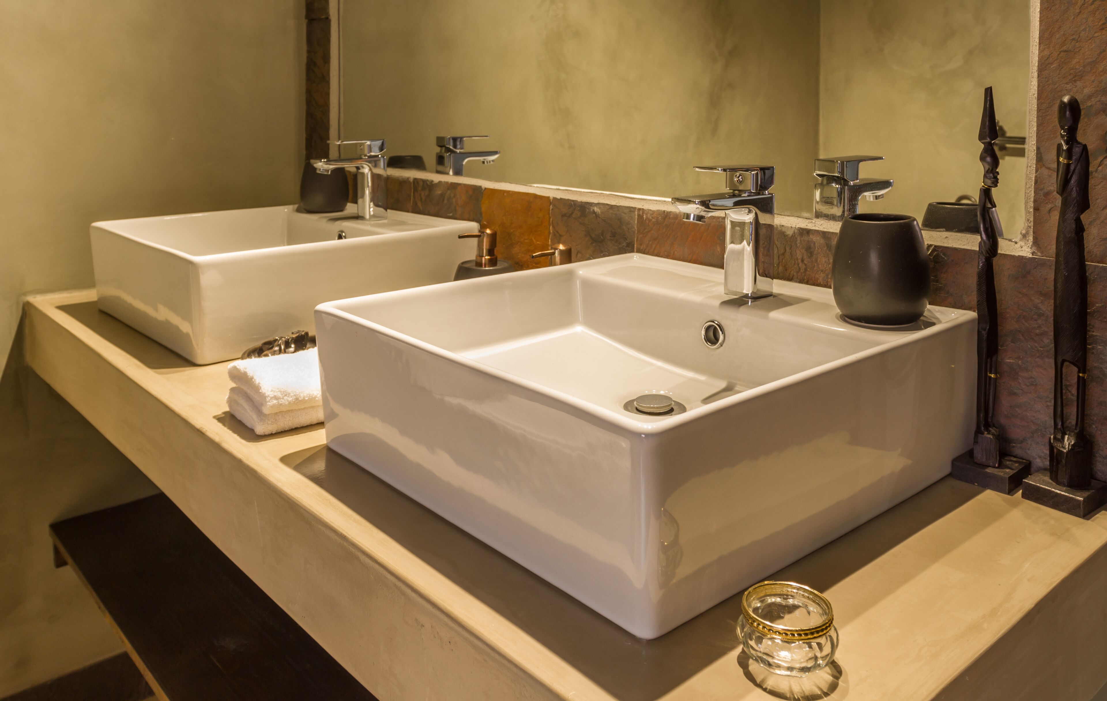 Une salle de bain moderne avec deux vasques blanches, un grand miroir et un plan de toilette en marbre.