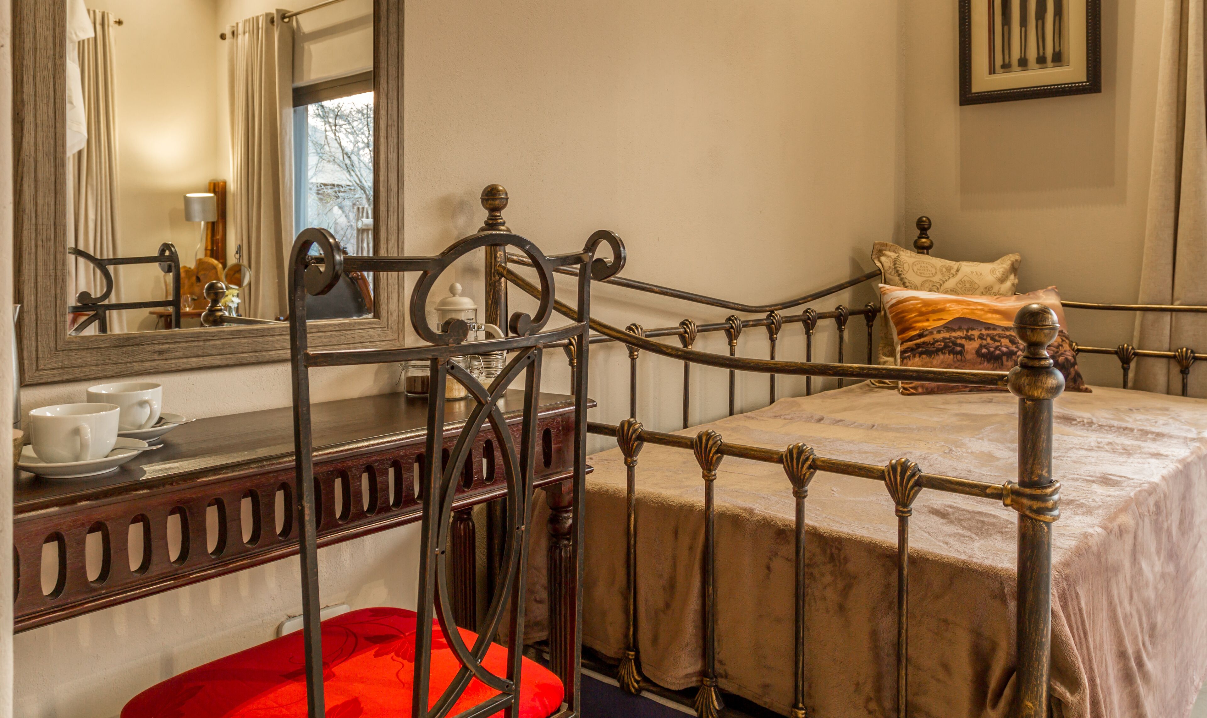 A bedroom with a metal bed frame, a bedside table with a lamp, and a window with curtains.
