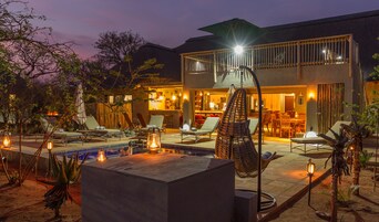 Un edificio de dos pisos con bar, comedor, terraza y piscina.