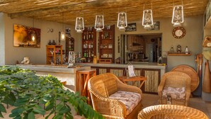 A cozy bar area with wicker furniture, hanging lanterns, and a variety of bottles and glasses on shelves. - Ukuthula Bush Lodge (Hoedspruit)