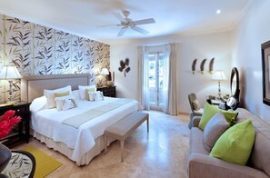 A bedroom with a large bed, a sofa, a desk, and a ceiling fan.