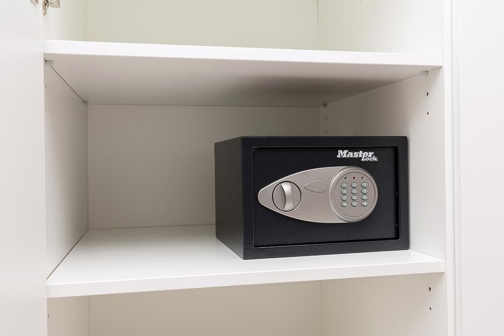 Un coffre-fort Master Lock noir, placé dans un meuble blanc.