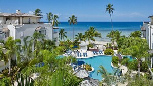 A resort with a pool, palm trees, and a view of the ocean. - Schooner Bay 206 - Condothe Palms (Speightstown)