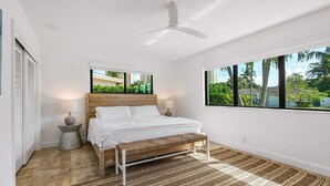 A bedroom with a bed, a ceiling fan, a window with a view of palm trees, and a textured rug. - Yacht Harbor Oasis: Beach Bliss with Private Pool  (West Palm Beach)