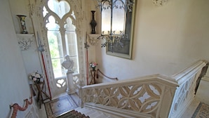 Una imponente escalera con barandillas blancas decoradas y un suelo con diseño.