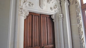 Una puerta de madera ornamentada con intrincados grabados y un arco decorativo encima.