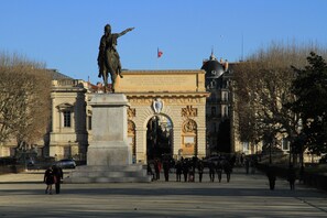 A historical monument with inscriptions, surrounded by a plaza with pedestrians and cars. - Hôtel des Etuves (Montpellier)
