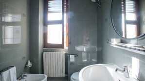A bathroom with two sinks, a toilet, a shower, and a window.