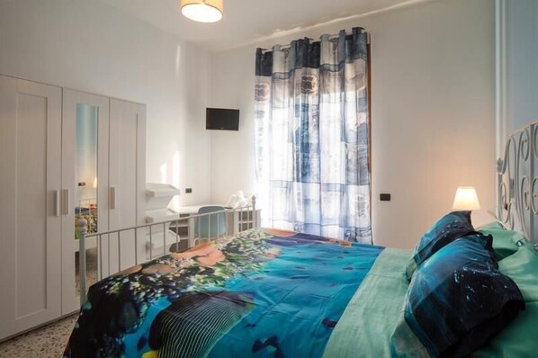 Un dormitorio con cama, escritorio y armario.