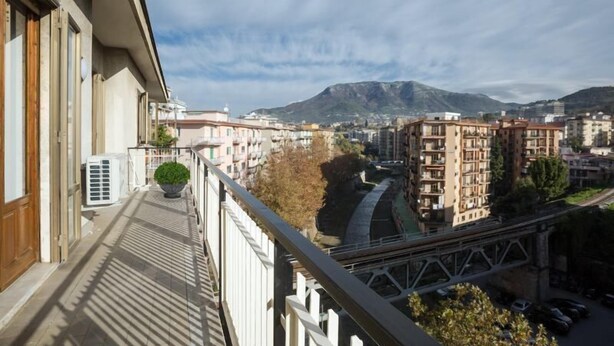 A balcony with a view of a river, buildings, and a mountain in the distance.