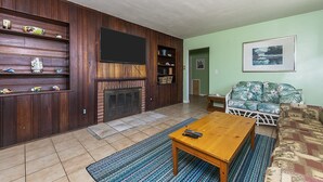 A living room with a fireplace, wooden shelves, a television, a sofa, and a coffee table.