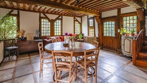 Un comedor rústico con una mesa y sillas de madera, rodeado de amplios ventanales y vigas de madera.