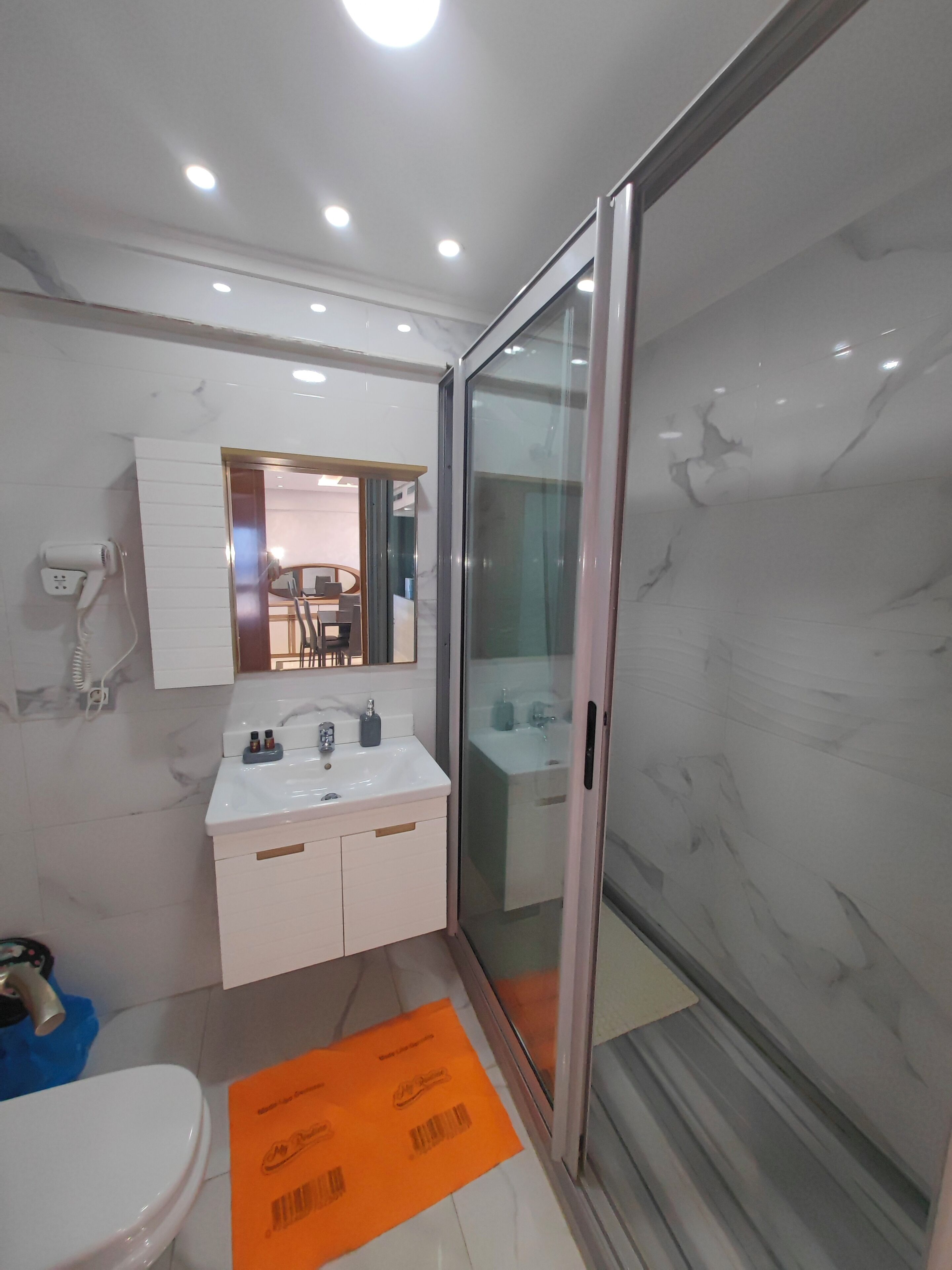 A modern bathroom with a white sink, mirror, and toilet.