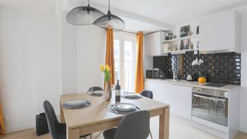 Una cocina moderna con una mesa de comedor de madera, gabinetes blancos y negros, y un salpicadero de azulejos negros.