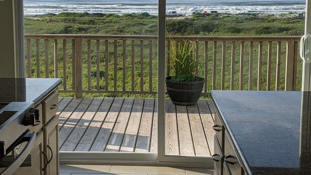 A balcony with a view of the ocean, a wooden deck, and a potted plant. - Golden Surfside--It has GOLDEN VIEWS and it's brand new!! (Surfside Beach)