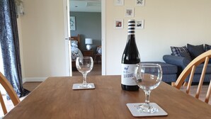 A wooden dining table with two wine glasses and a bottle of Giroud wine. - Swallows Nest, Cottage, Fishing Lakes Nr Cleethorpes, Adults Only Pet Friendly  (Lincolnshire)