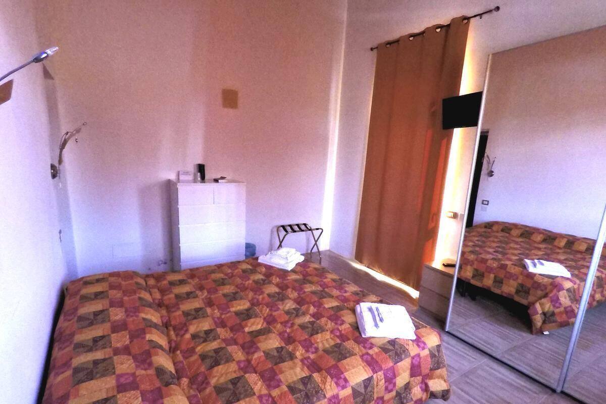 A hotel room with a large bed, a bedside table, a mirror, and a wardrobe.