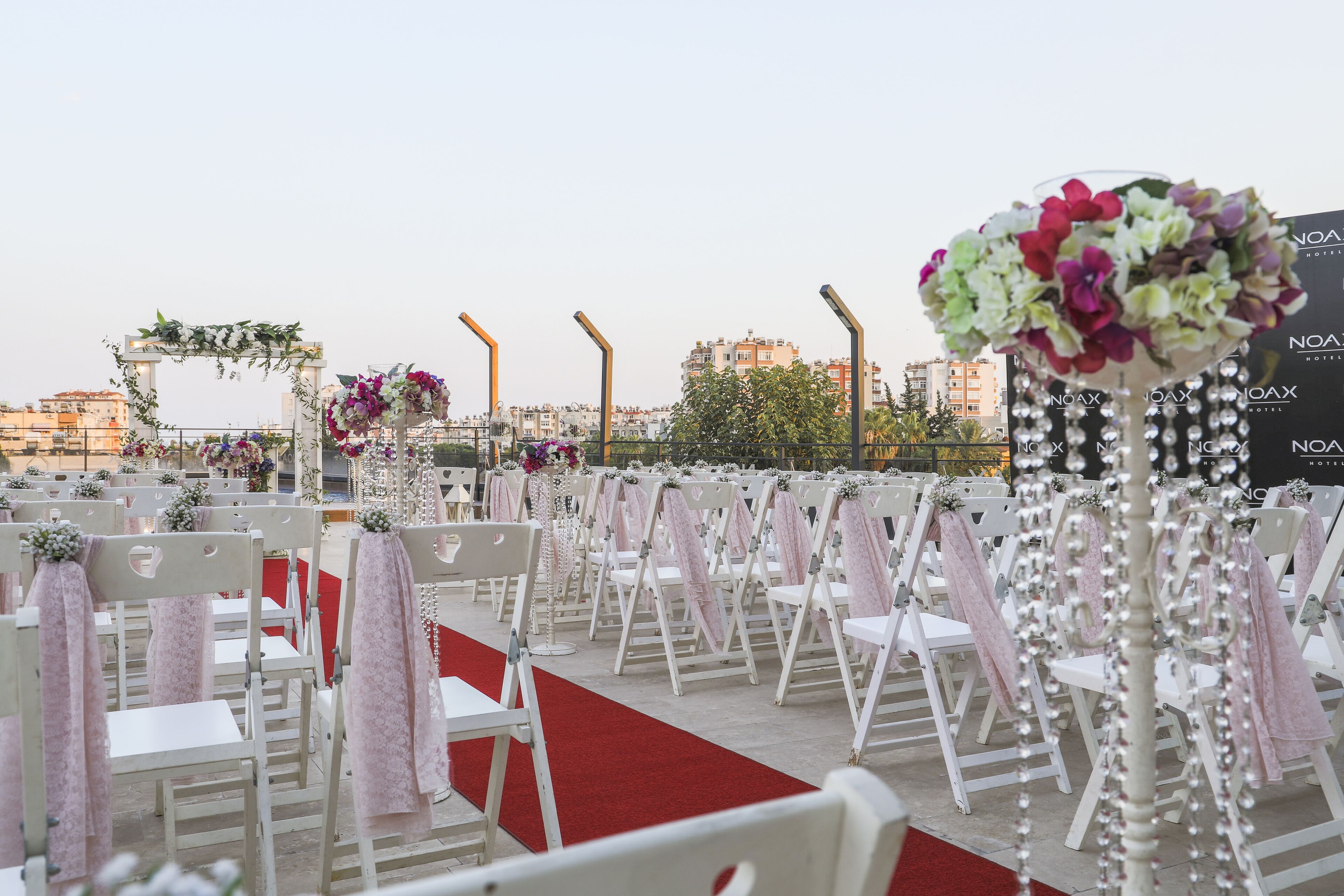 A wedding ceremony setup with white chairs, a red carpet, and floral decorations.