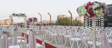 A wedding ceremony setup with white chairs, a red carpet, and floral decorations.