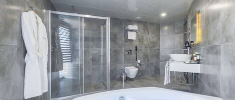 Un baño moderno con ducha envuelta en vidrio, una bañera independiente y un tocador con lavamanos y espejo.