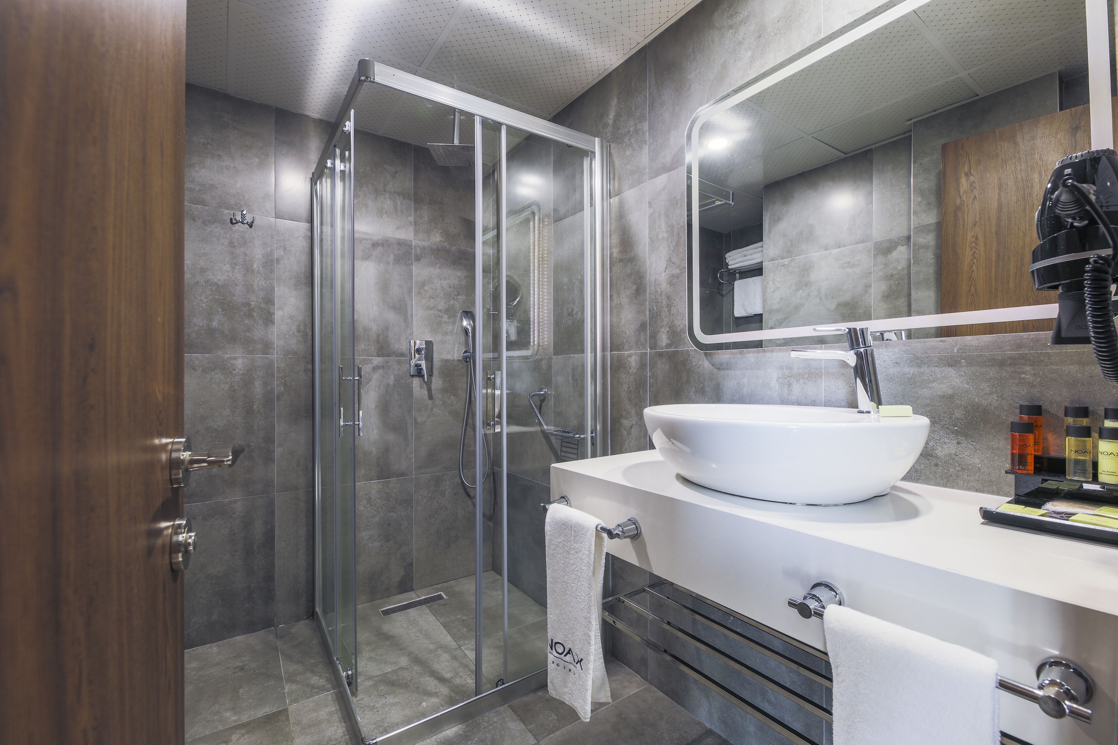 A modern bathroom with a glass-enclosed shower, a white sink, and a large mirror.