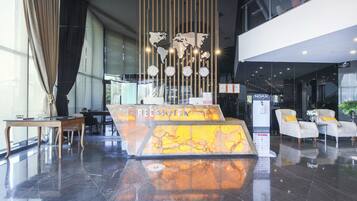 A reception area with a marble counter, a world map, and clocks.