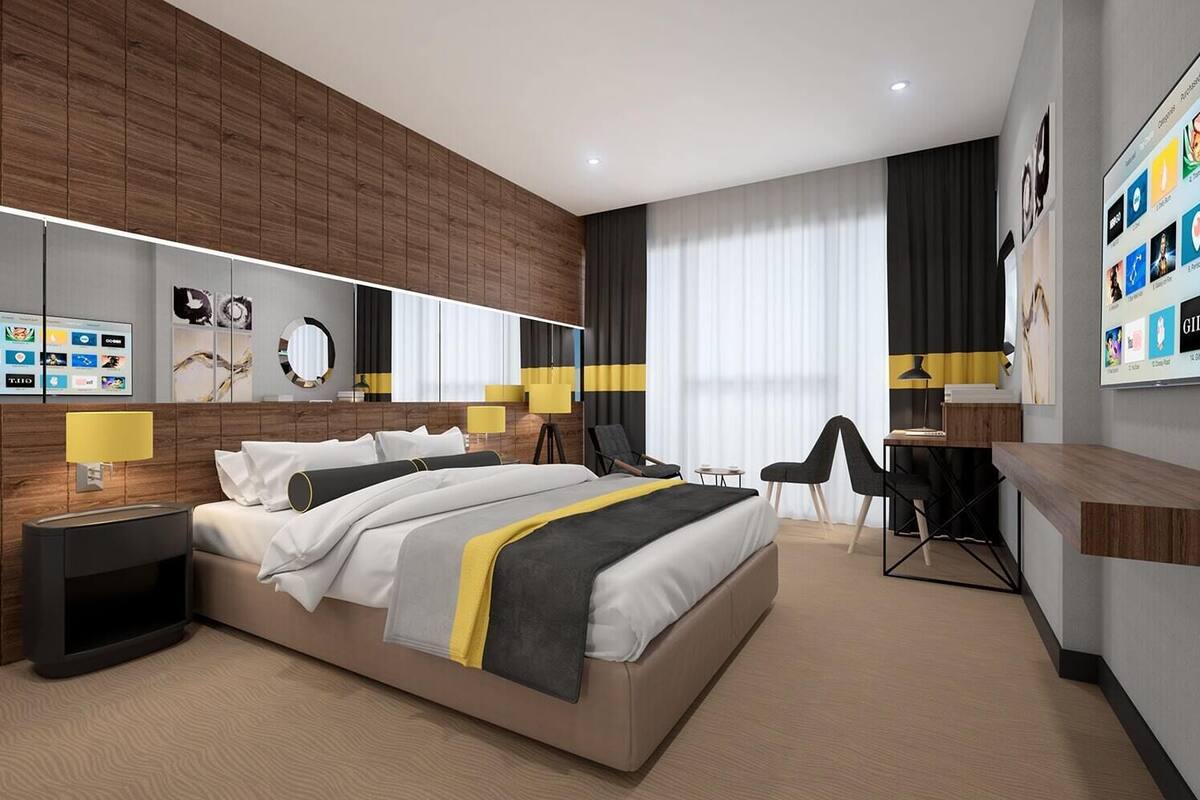A modern hotel room with a large bed, a desk, and a seating area.