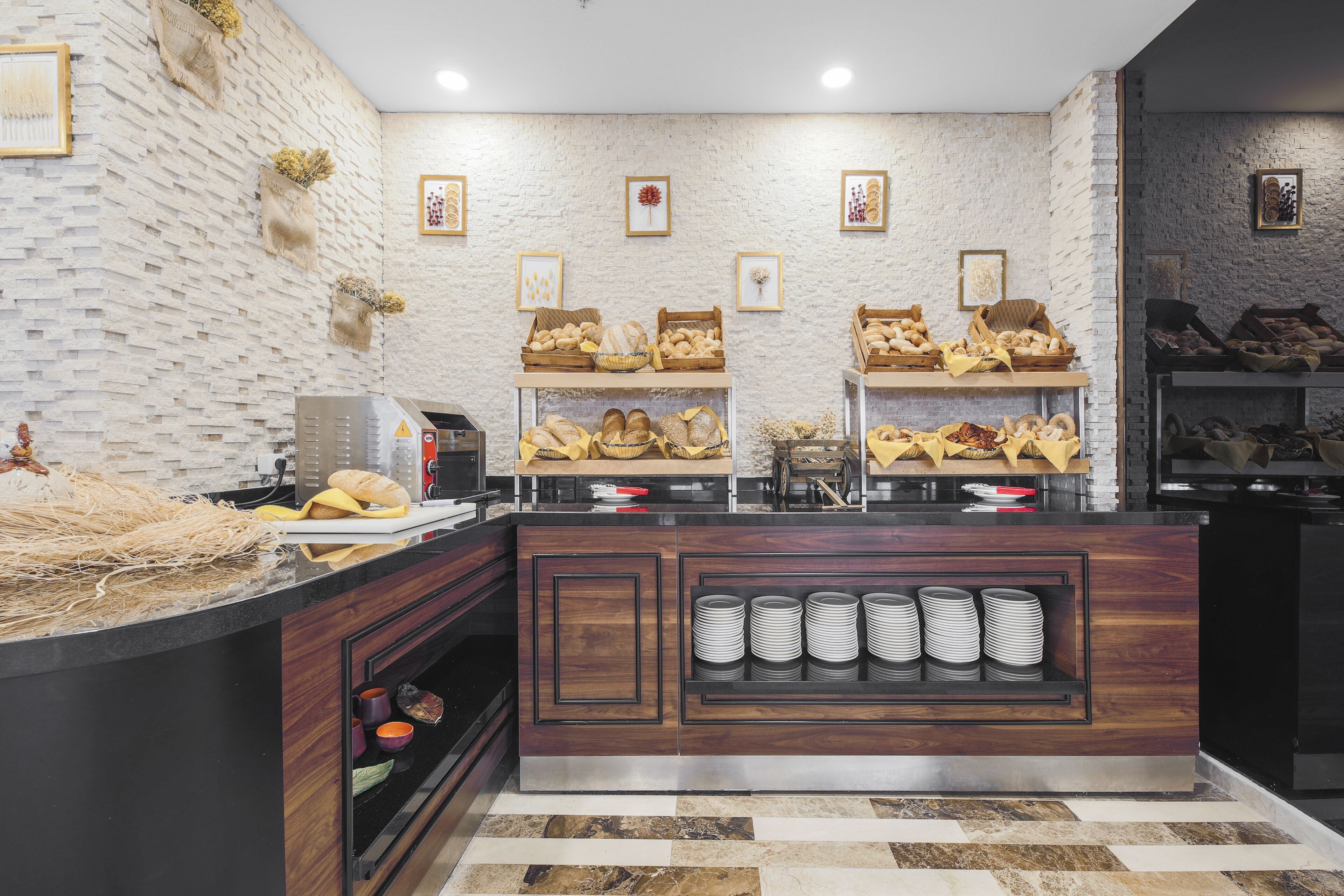 A bakery counter with bread and pastries, a coffee machine, and a display of plates and cups.