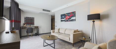 Una sala moderna con un sofá, dos mesas de centro, un escritorio y una lámpara.