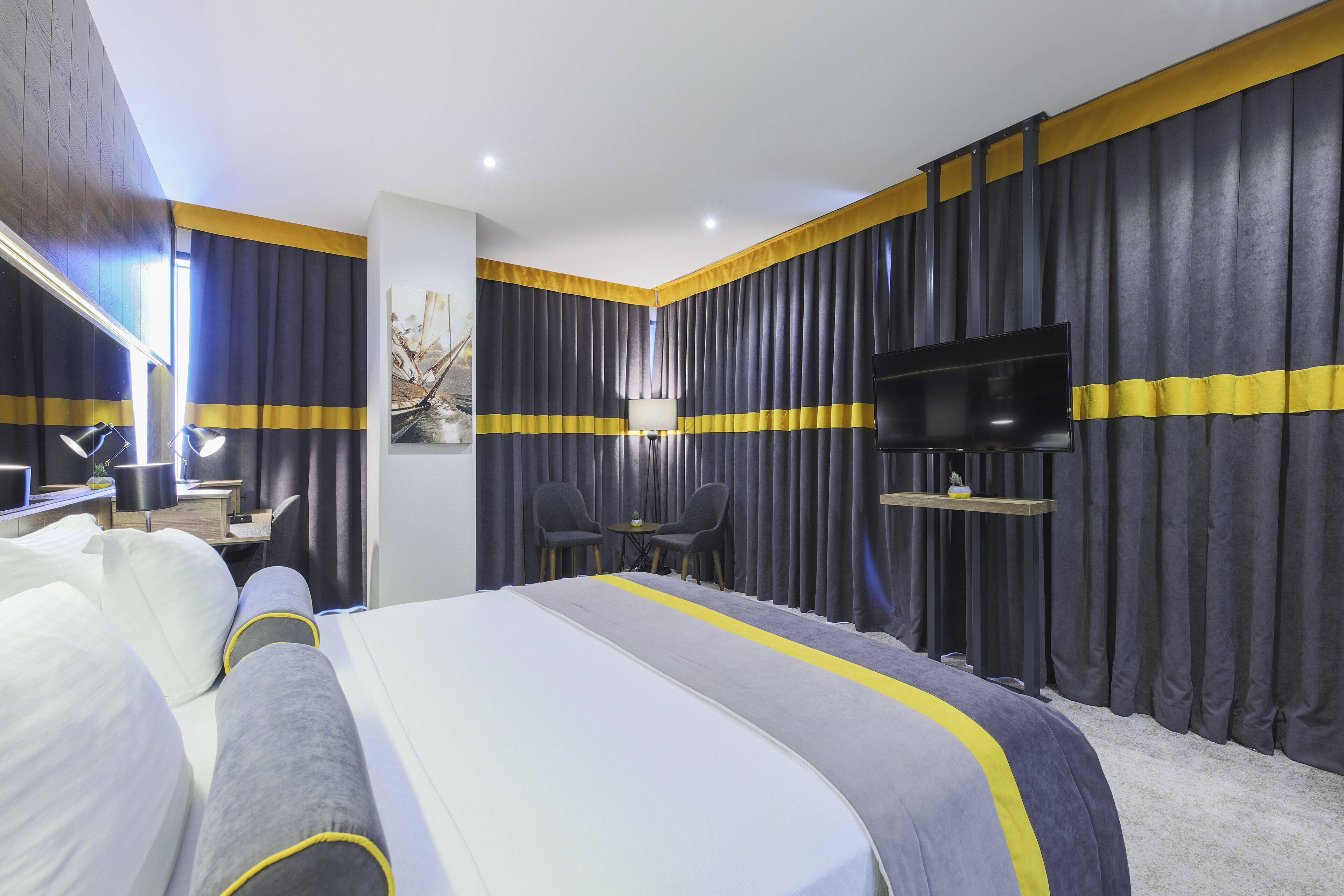 Una habitación de hotel moderna con una cama grande, un escritorio con una silla, un televisor y una mesita.