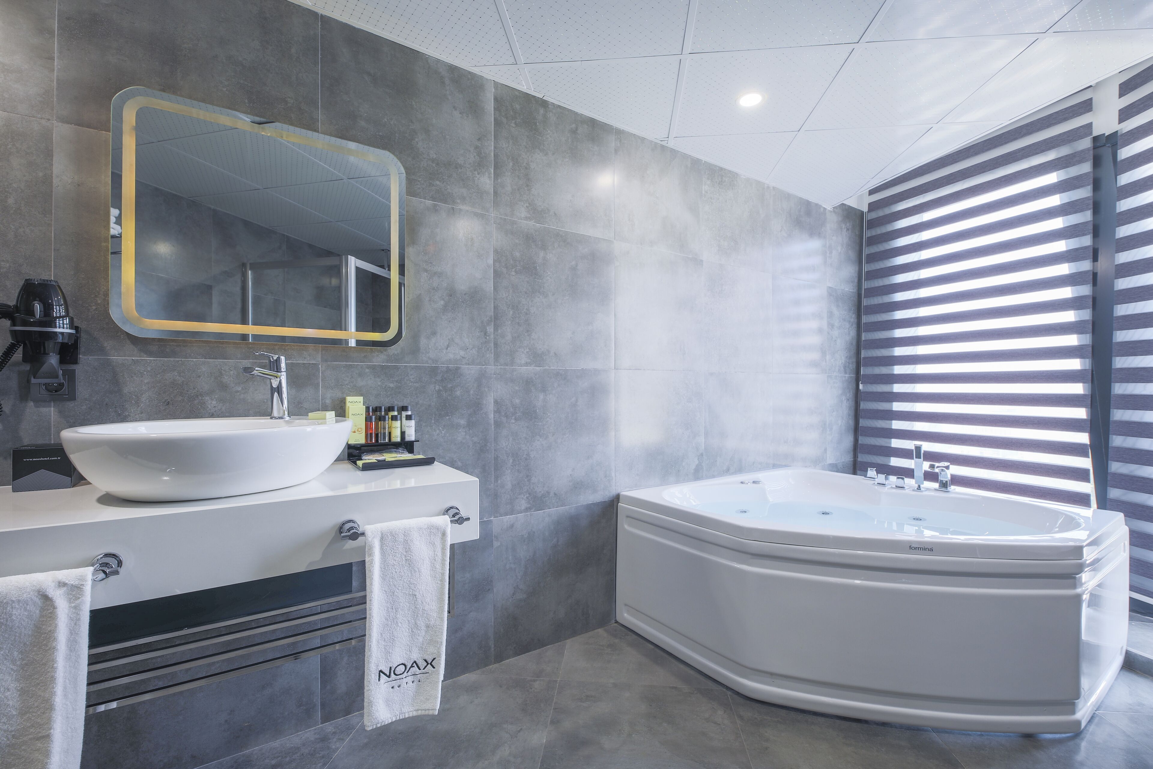 A modern bathroom with a large freestanding bathtub, a round sink, and a mirror with a gold frame.