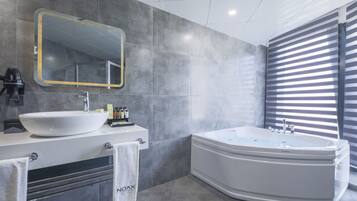 A modern bathroom with a large freestanding bathtub, a round sink, and a mirror with a gold frame.
