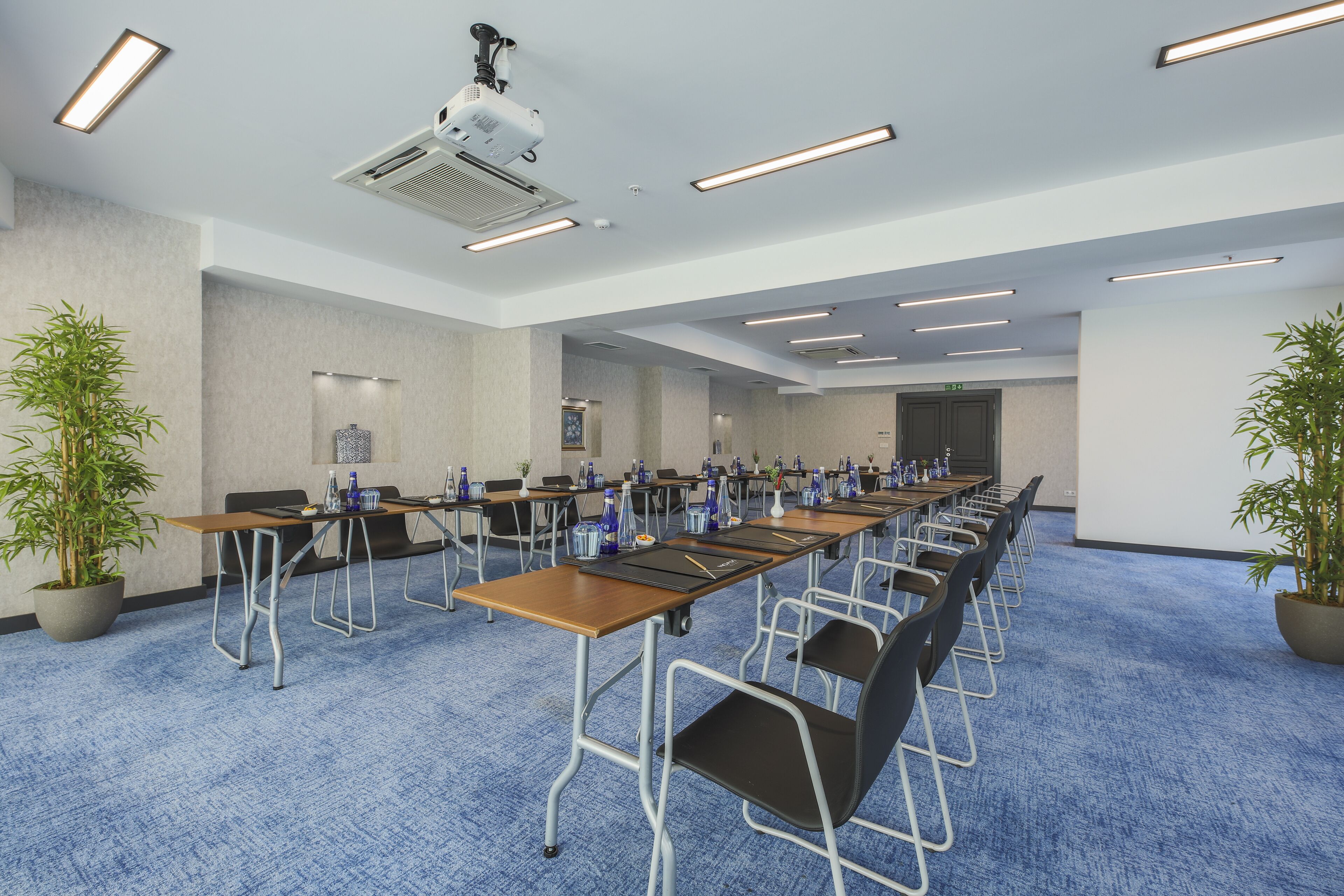 A conference room with long tables, chairs, and a projector.