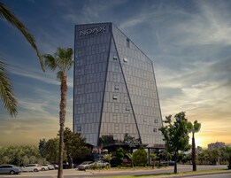 Un hotel moderno con una fachada de vidrio destacada y un diseño triangular distintivo.