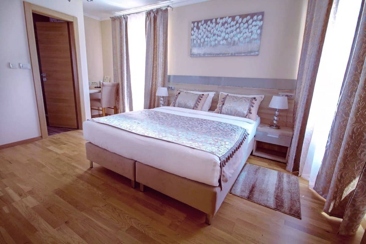Un dormitorio con una cama grande, mesitas de noche, un escritorio y una silla.