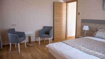 Una habitación de hotel con una cama, dos sillones, una mesita redonda y un armario de madera.