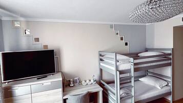 A compact hotel room with a bunk bed, a desk with a television, and a small seating area.