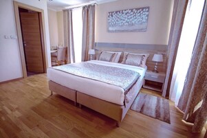 Un dormitorio con una cama grande, una mesita de noche con lámpara, una silla y un cuadro en la pared.