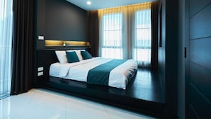A modern bedroom with a large bed, dark walls, and a window with curtains. - 42 Grand Residence (Bangkok)