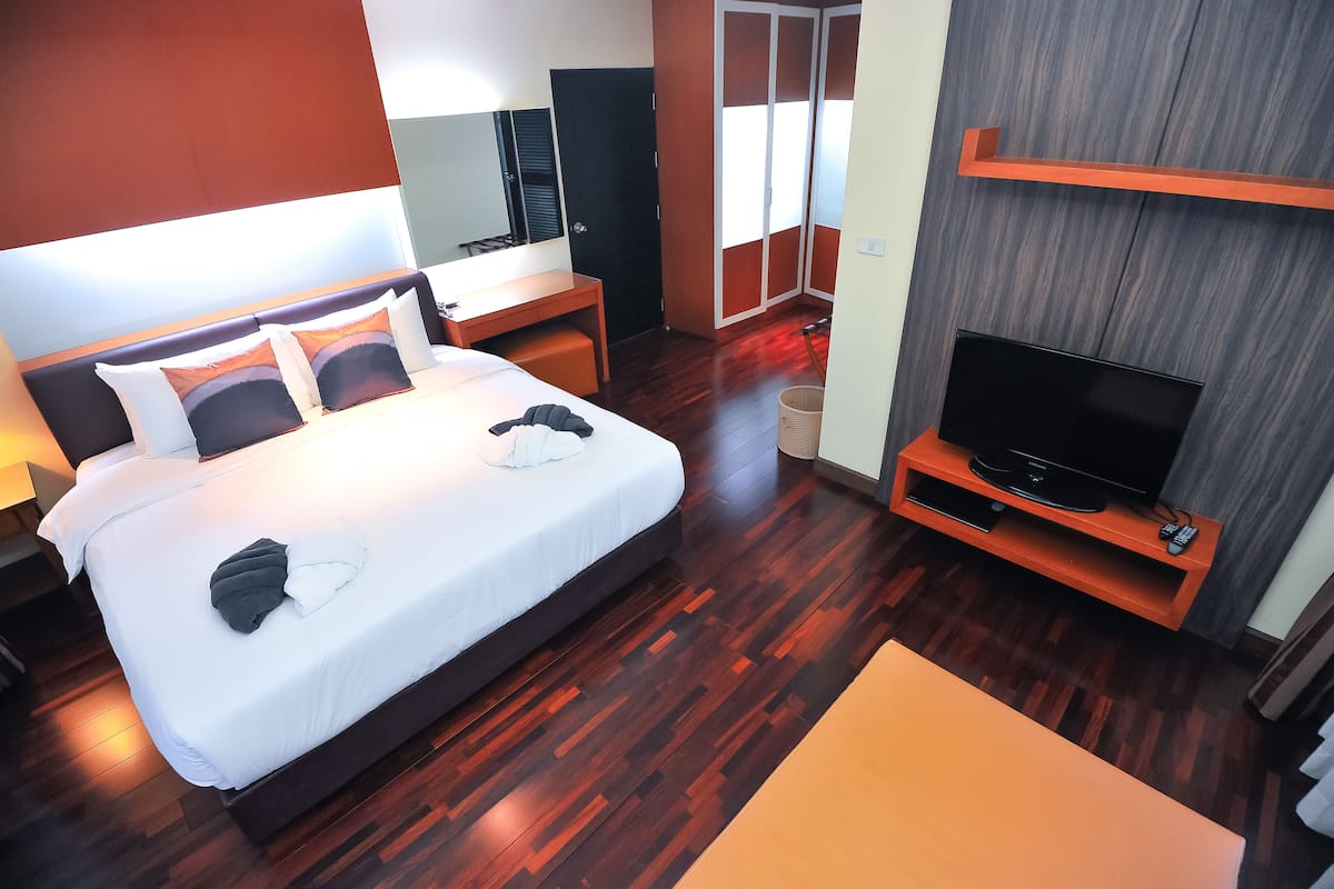 Une chambre d’hôtel moderne équipée d’un grand lit, d’une table de chevet, d’une télévision et d’une armoire.