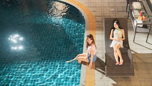 A poolside area with a lounge chair and a table with fruits and a drink. - 42 Grand Residence (Bangkok)