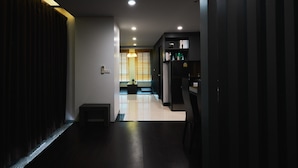 A hallway with a dark floor, a light fixture, and a bookshelf with items on it. - 42 Grand Residence (Bangkok)