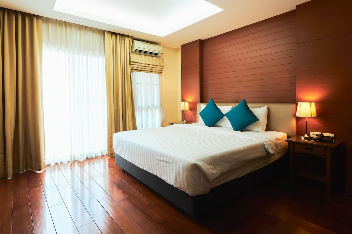 Une chambre d’hôtel avec un grand lit, un plancher en bois, une lucarne et deux lampes de chevet.