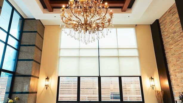 A spacious lobby with a large chandelier, a sofa set, and a view through large windows. - 42 Grand Residence (Bangkok)