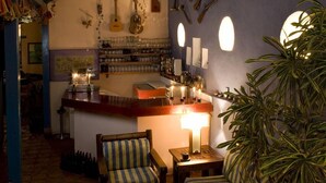 Un espace bar accueillant, avec un comptoir, des tabourets de bar et un coin salon agrémenté d’un canapé à motifs.