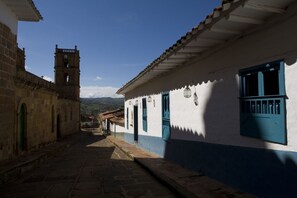 Une rue étroite bordée de bâtiments traditionnels, un clocher et un ciel dégagé.