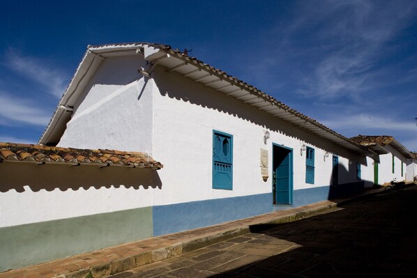Un bâtiment blanc avec des portes et des fenêtres bleues, un toit en tuiles et une rue pavée.