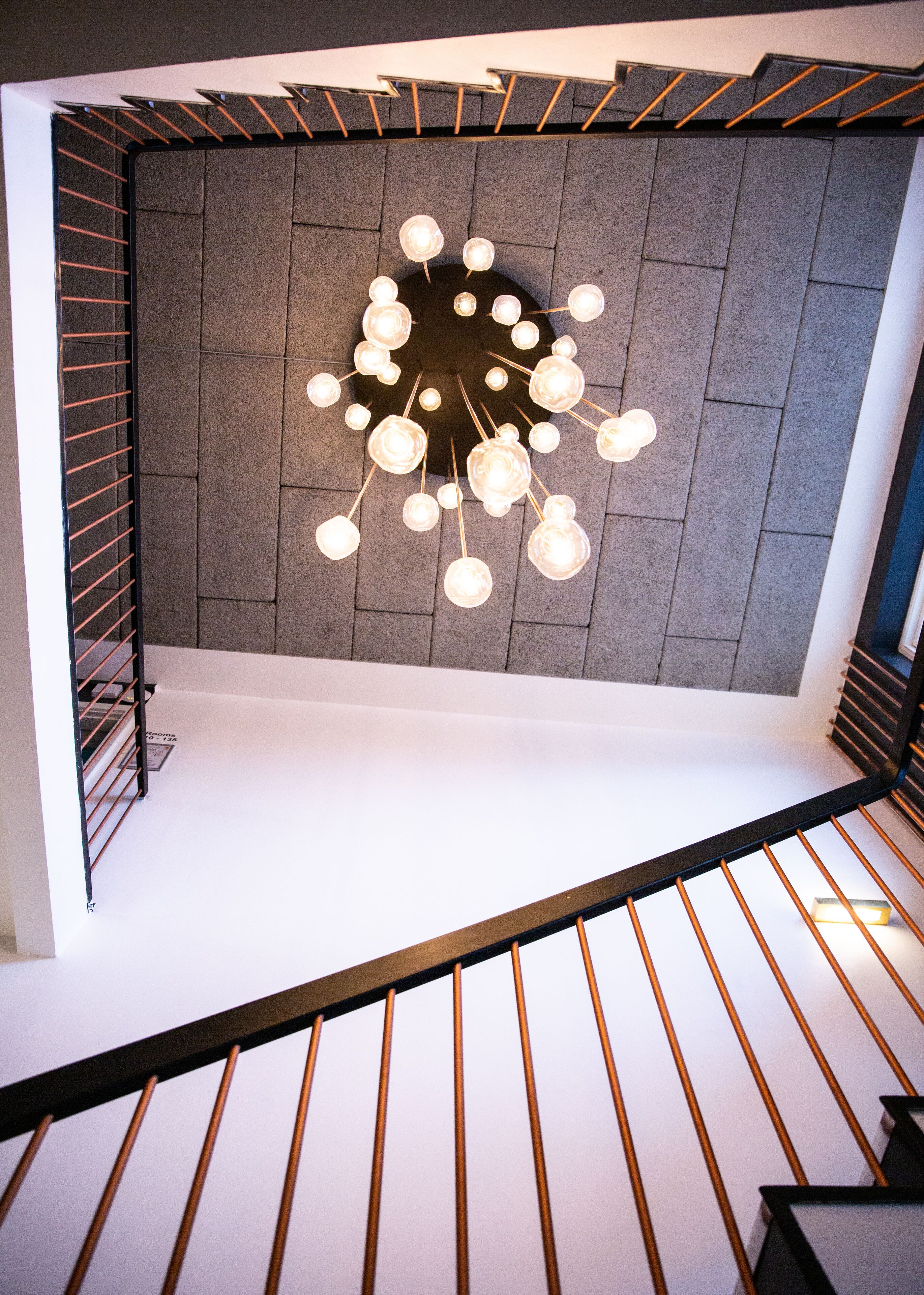 A modern staircase with a metal railing and a wall-mounted light fixture with multiple bulbs.