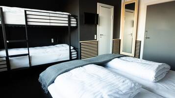 A hotel room with bunk beds, a television, a wardrobe, and a mirror.
