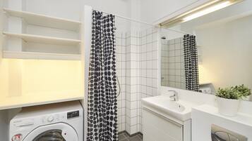 Ein kleines Badezimmer mit Waschmaschine, Waschbecken und Spiegel.